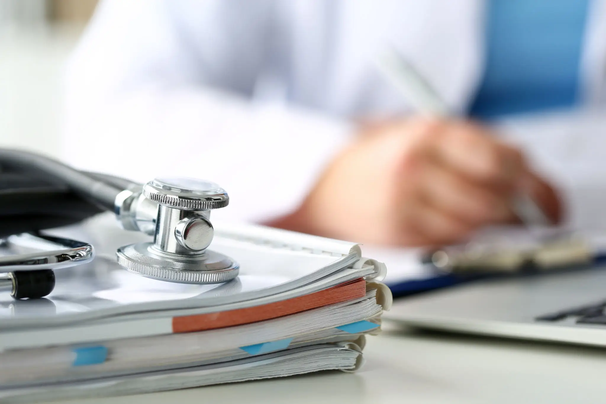 Stethoscope resting on stacked medical documents